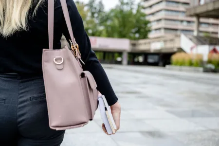 Studentin trägt Tasche und Bücher. 