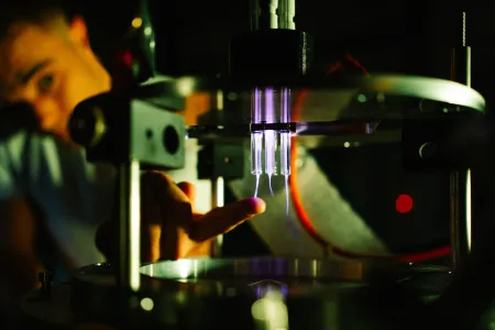 Eine Person fasst in eine Apparatur, in der es violett leuchtet