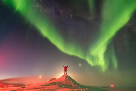Person im Schnee, darüber Polarlichter