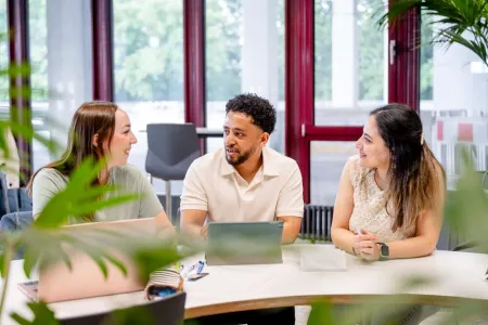 3 Studierende sitzen vor einem Laptop.
