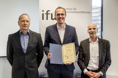 Drei Männer, einer davon hält eine Urkunde