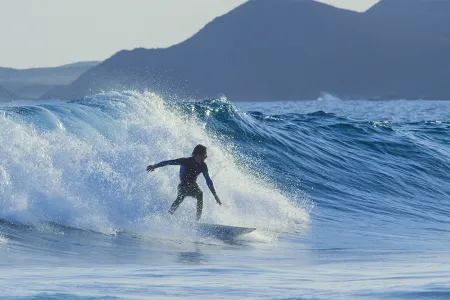 Surfer im Wasser vor einer Welle